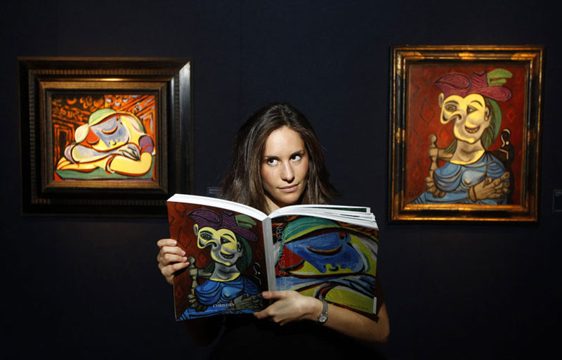A Christie's Auction House staff with Pablo Picasso's Jeune Fille Endormie and Femme Assise, Robe Bleue